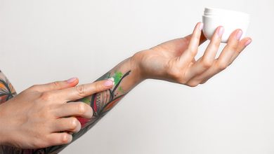 persona che spalma crema su tatuaggio pelle